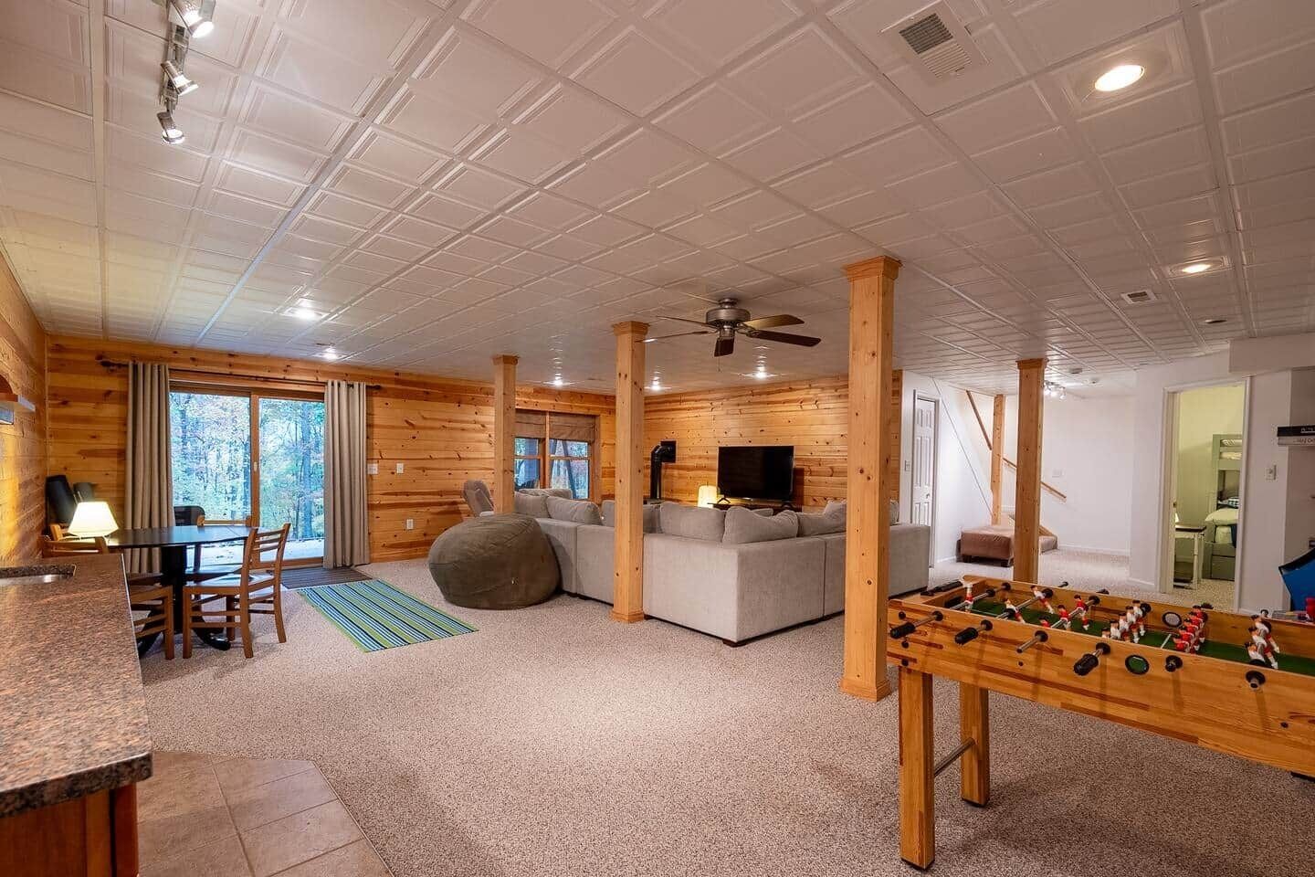Een gezellig chaletinterieur met een eethoek, een bank en een tafelvoetbaltafel.
