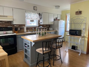 Une cuisine dotée d’un îlot central, de tabourets de bar, d’un four à micro-ondes et d’un réfrigérateur.