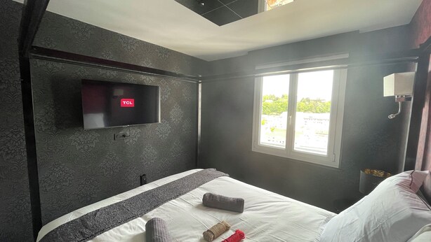 Une chambre d’hôtel avec un lit, une télévision, une fenêtre et une vue sur l’extérieur.