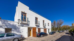 En moderne bygning med hvid facade, flere balkoner og en brostensbelagt gade.