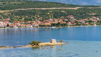 A coastal town with houses along the shoreline and a small island with a tower.