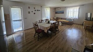 Amplia sala de estar con una mesa de comedor, sillas, un sofá y una televisión.