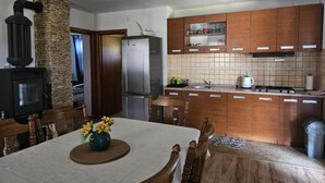 Una cocina con armarios de madera, un pilar de piedra, una estufa y una mesa de comedor con sillas.