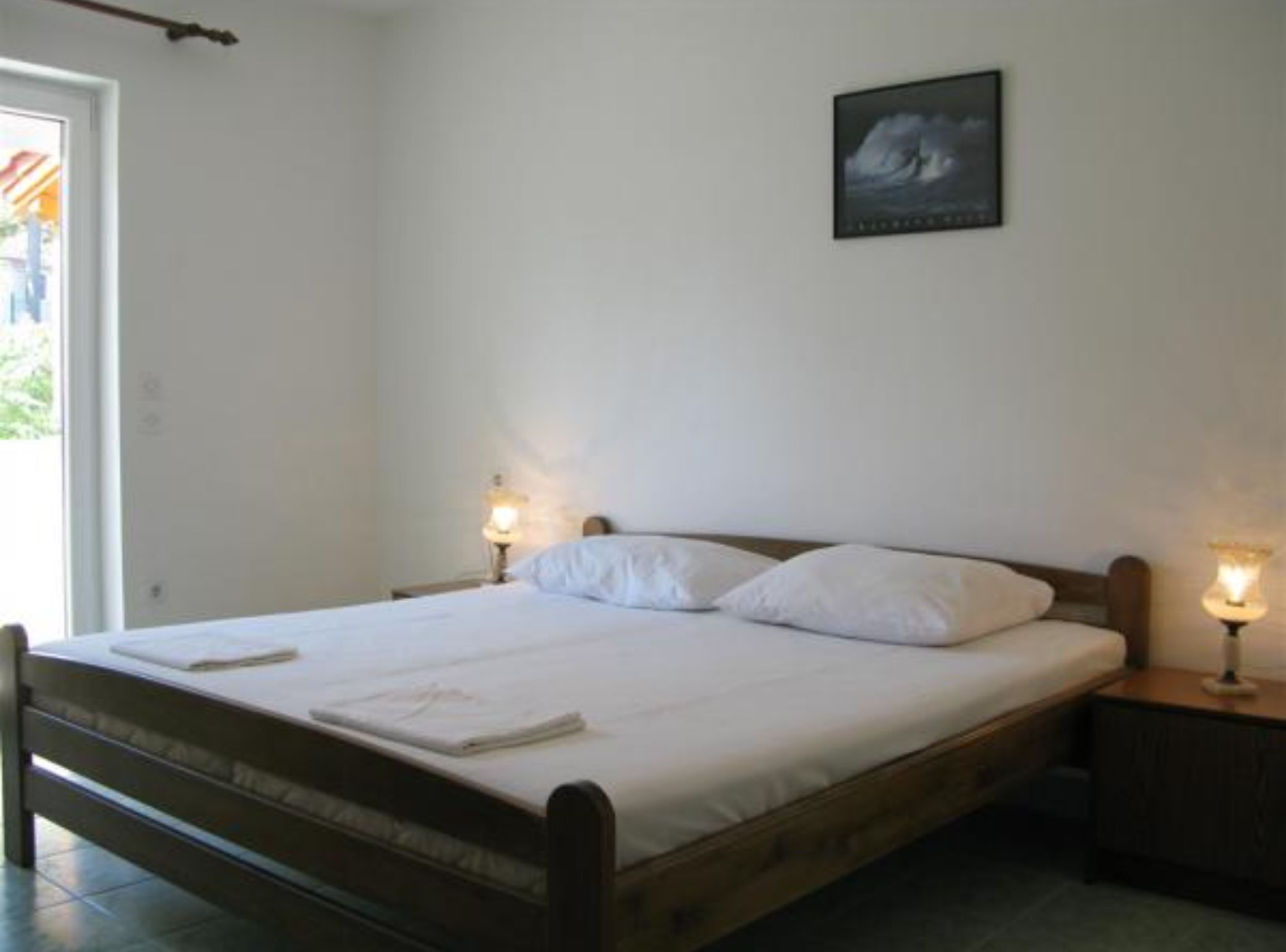 A single bed with white bedding, two bedside tables with lamps, and a framed picture on the wall.