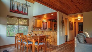 Un comedor con mesa y sillas de madera, una cocina con armarios de madera y una sala de estar con sofá.