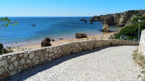 A coastal view with a stone pathway leading to a beach, clear blue sea, and rocky cliffs. - Casa Pimenta near the beach, Iberlagos Resort (Lagos)