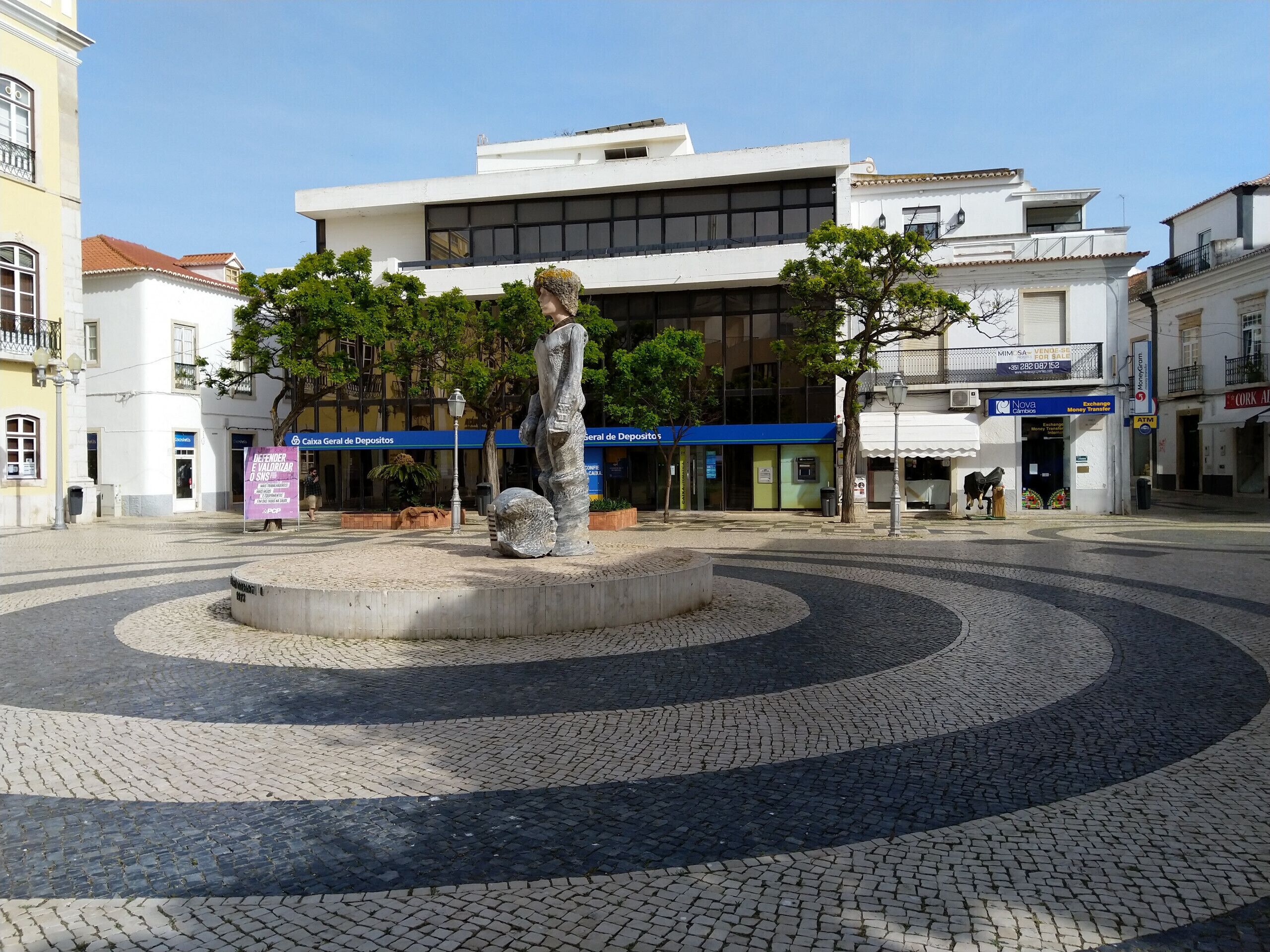 Una plaça amb una escultura central, envoltada d'elements decoratius de pedra.