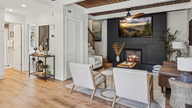 Una sala de estar con chimenea, un sofá, una mesa de centro y un comedor con sillas.