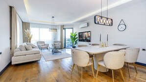 Un salon moderne comprenant un canapé, des fauteuils, une table à manger et un téléviseur.