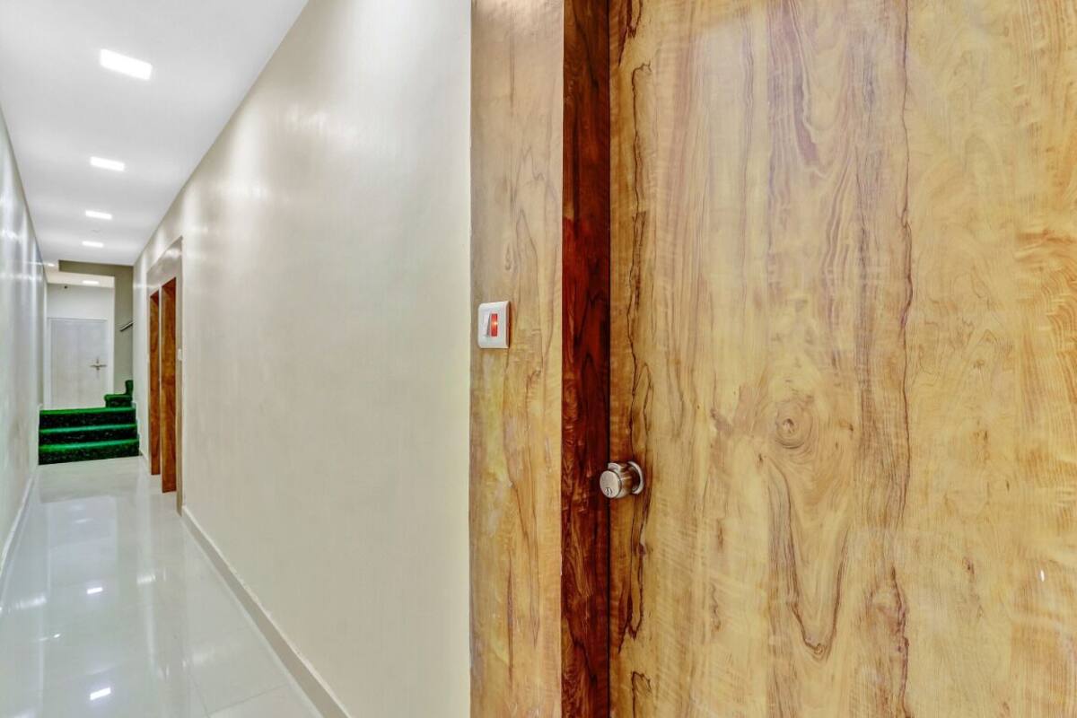 A hallway with a wooden door, a light switch, and a staircase in the background.