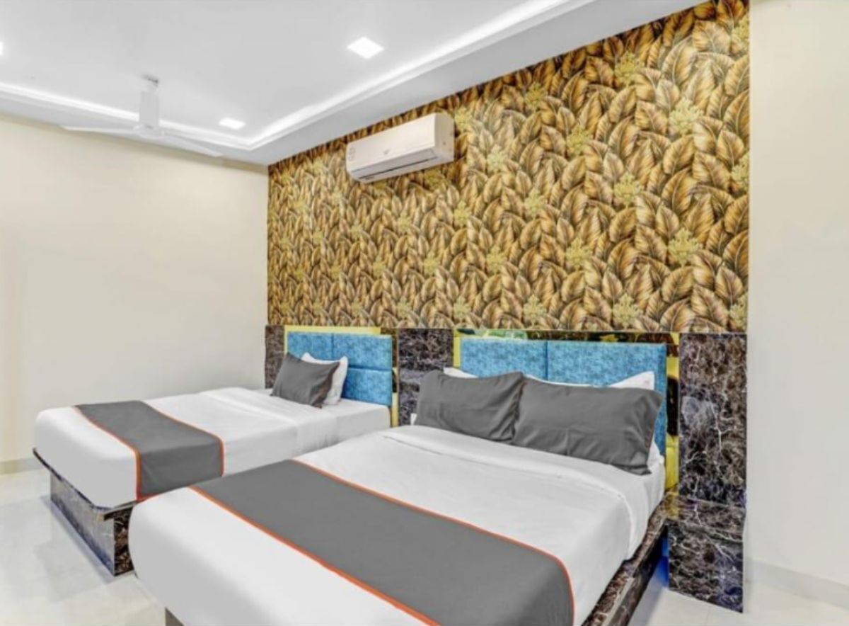 A hotel room with two beds, each with grey and orange bedding, and a textured wall behind them.