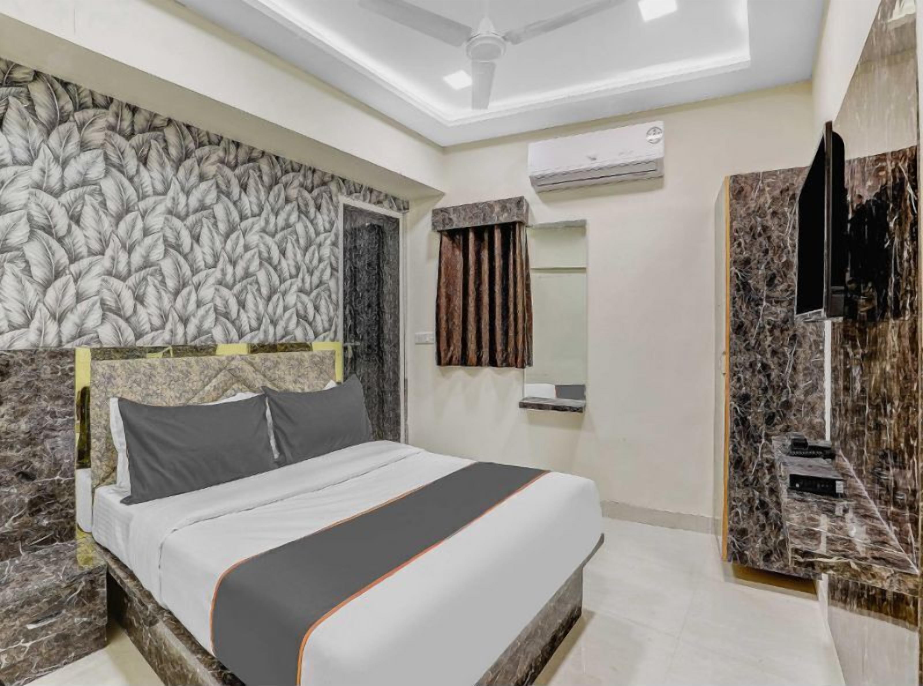 Una habitación de hotel moderna con cabecera de mármol, una cama grande, aire acondicionado y televisión integrada.