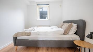 Un dormitorio con una cama, una mesita redonda y una ventana.