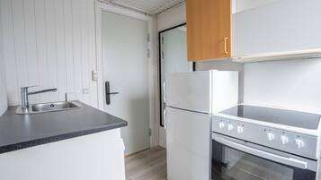 Comfort appartement | Privékeuken | Een magnetron, een oven, een kookplaat, kookgerei, borden en bestek