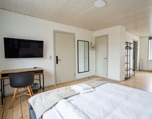 Un dormitorio con cama, escritorio, silla, televisor y armario.