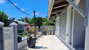 Uma casa moderna com um alpendre ladrilhado, portão fechado e um vaso de planta.