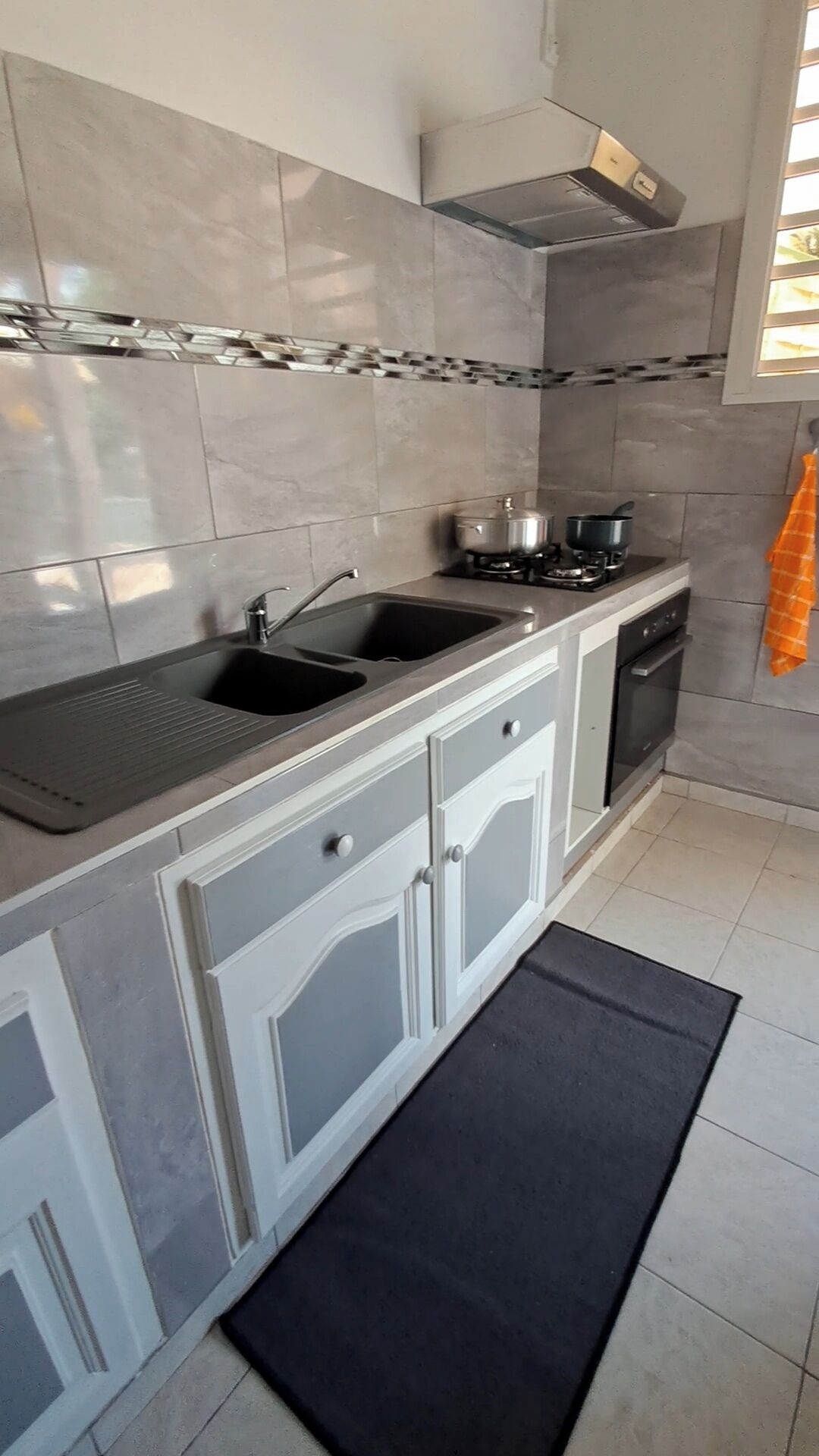 Een moderne keuken met twee spoelbakken, een fornuis en een vaatwasser.