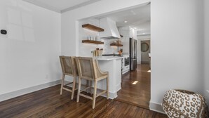 Una cocina moderna con armarios blancos, sillas de madera y una isla integrada.