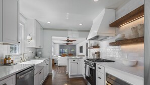 Una cocina moderna con muebles blancos, una isla central y un horno empotrado.