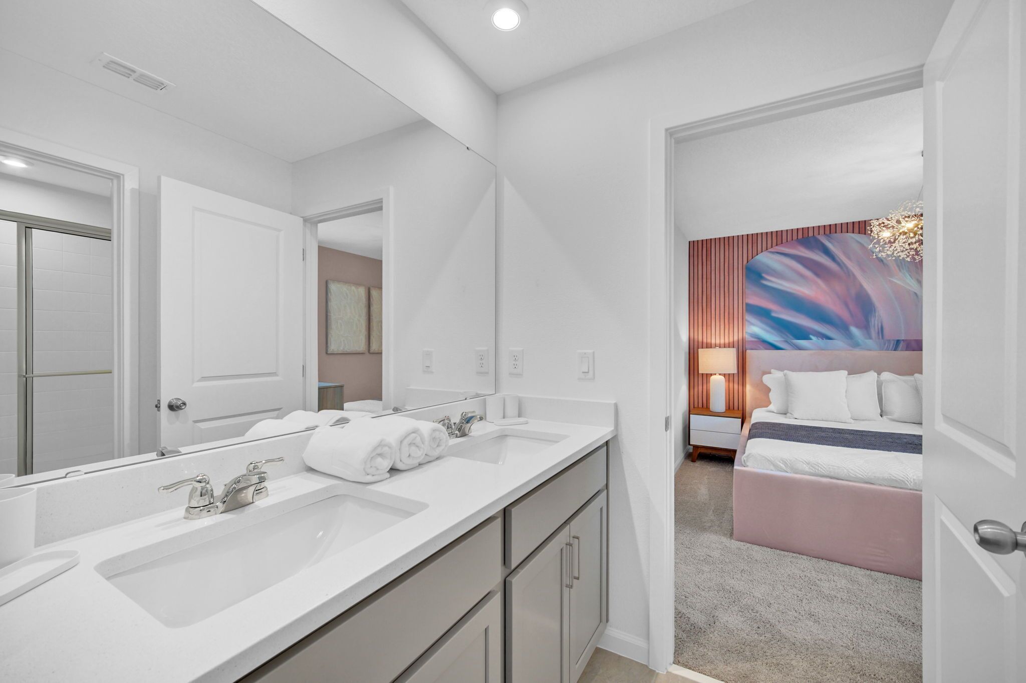 Un baño moderno con un espejo grande, dos lavamanos y un vestidor.