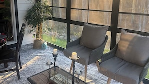 Een gezellig terras met een rieten bank, een bijzettafeltje en een potplant.