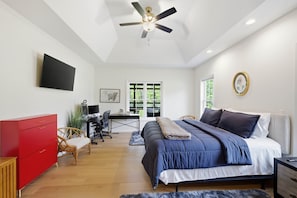 Ein Schlafzimmer mit einem Bett, einem Schreibtisch, einem Stuhl, einem roten Schrank und einem Deckenventilator.