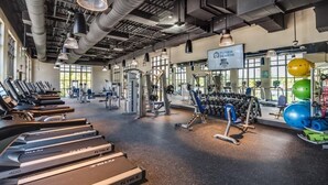 Una palestra con tapis roulant, macchinari per pesi e palle da ginnastica.