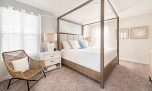 A bedroom with a four-poster bed, a wicker chair, a nightstand, and a dresser. - Spacious 5 Bed Pool Home with Game Room (Davenport)