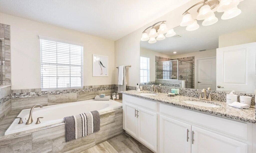A modern bathroom with a large bathtub, a double sink vanity, and a large mirror.