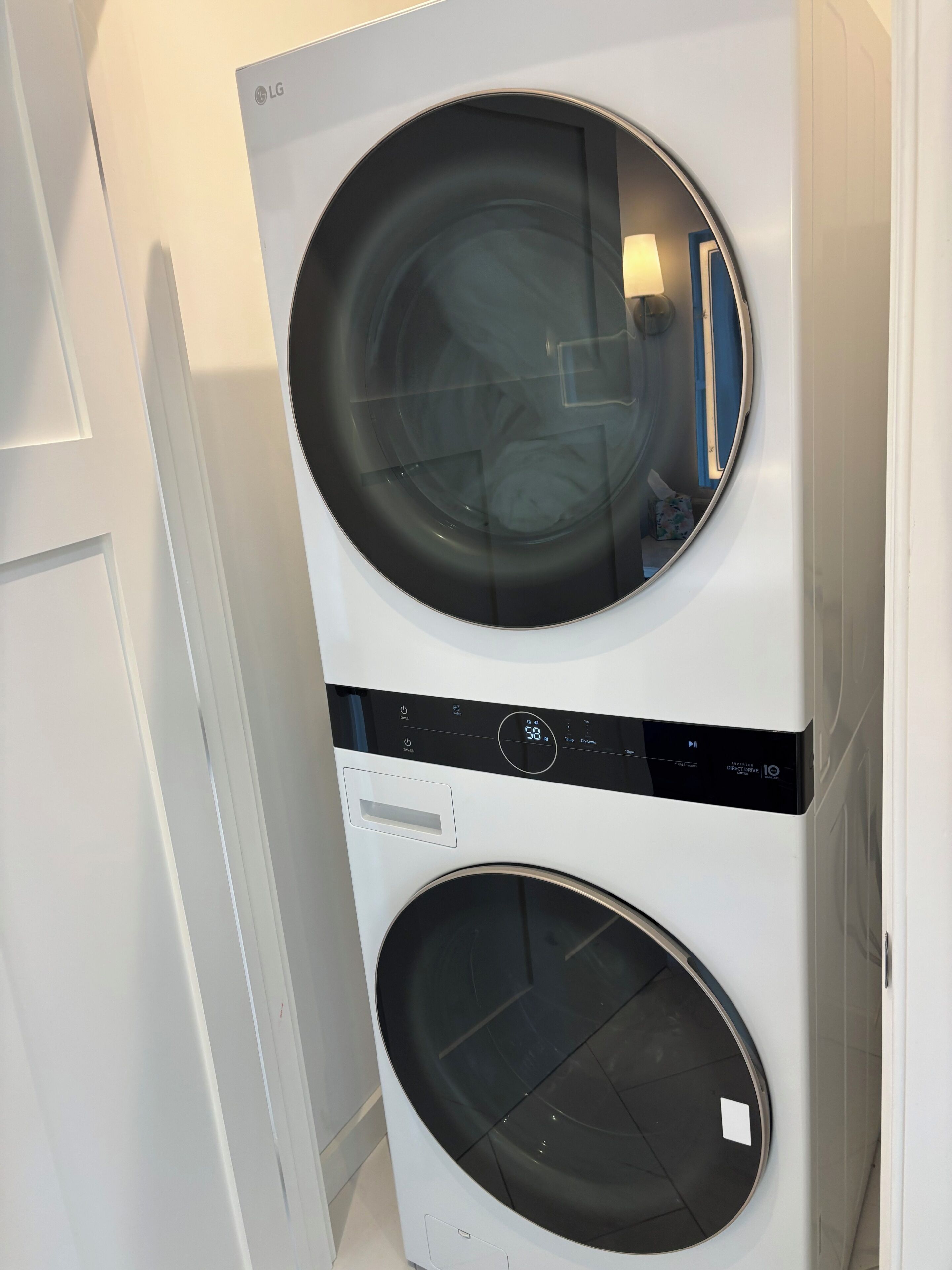 A front view of a stacked washer and dryer unit with a digital display and control panel.