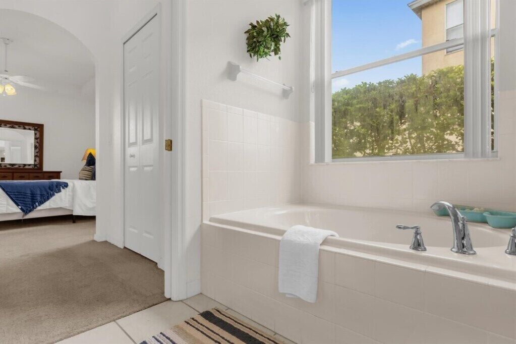 Un baño moderno con una bañera grande, una ventana con vistas a la vegetación y un espejo en la pared.