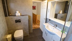 A modern bathroom with a toilet, sink, and mirror. - Luxe Leamington Spa Retreat (Royal Leamington Spa)