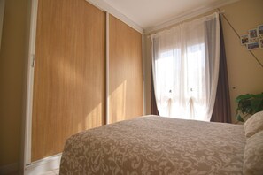 A bedroom with a bed, a wardrobe, and a window with curtains. - Bright apartament with pool (Golf del Sur)