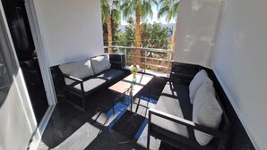 A balcony with a sofa, a small table, and a chair.