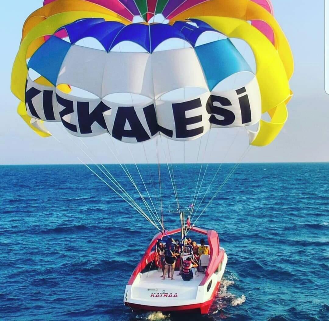 A parasailing boat with a colorful canopy and the word 'KIZKALASI' on it.