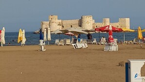 A beach with umbrellas, chairs, and a castle-like structure in the background.