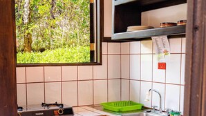 Eine kleine Küche mit Gasherd, Toaster und Blick auf Grünflächen.