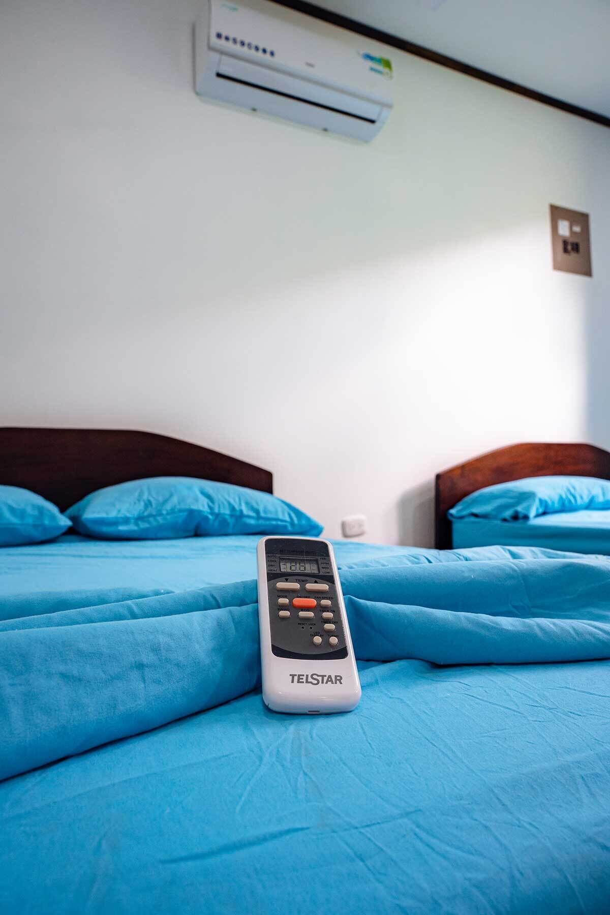 Una cama con ropa de cama azul y un control remoto Telstar encima.