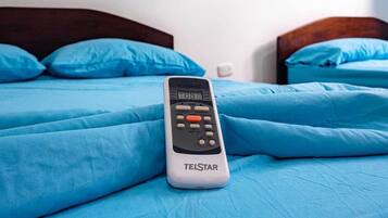 Una cama con ropa de cama azul y un control remoto Telstar encima.