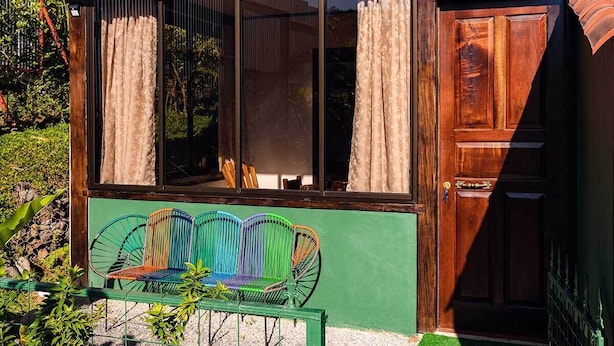 A wooden door with a window above it, a green bench outside, and a wooden fence. - Marte Dream Beach Shelter (Montezuma)