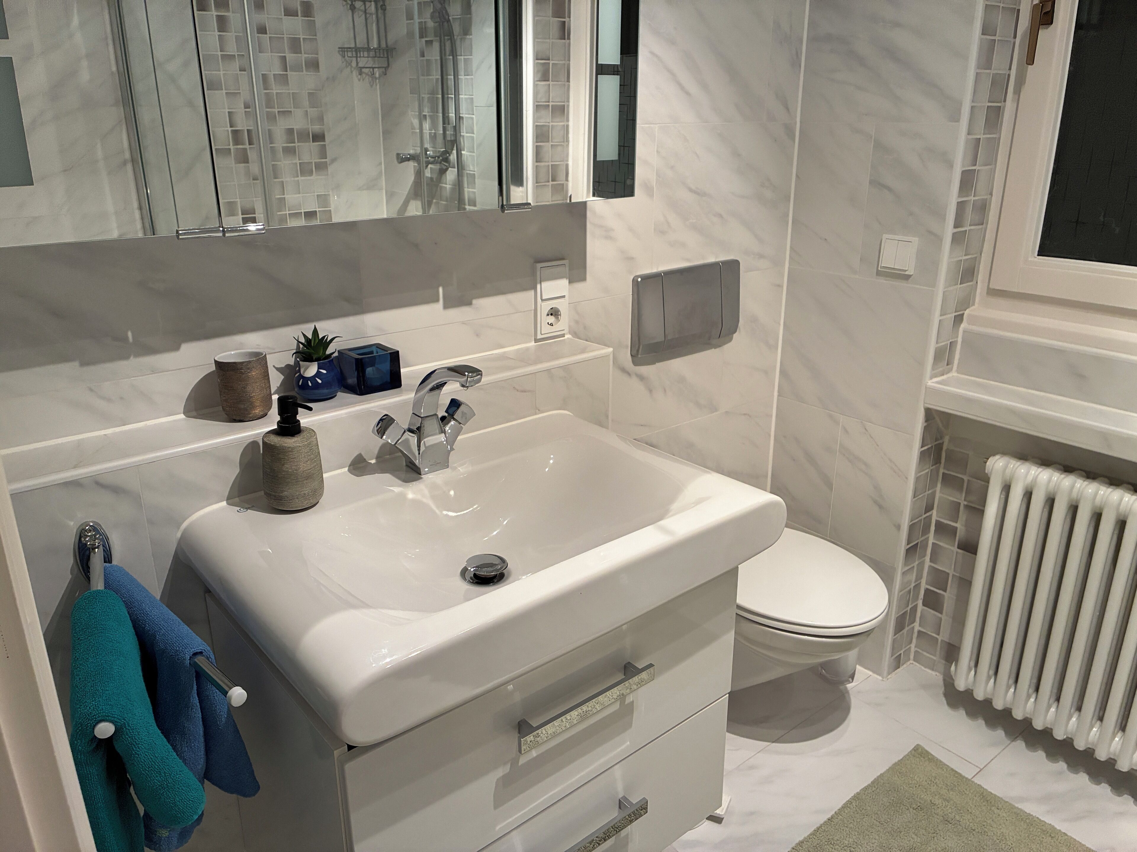 Une salle de bain moderne avec un lavabo blanc, un miroir, des toilettes et un radiateur.
