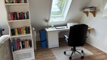A home office with a desk, chair, bookshelf, and a window with a view.