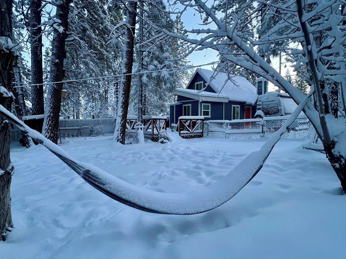 Een hangmat in een besneeuwde buitenomgeving, met een huis op de achtergrond.