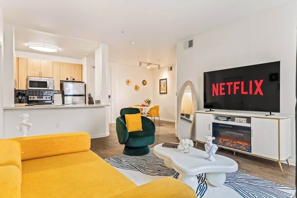 Spacious living area flooded with natural light, designed in warm tones with emerald accents - the perfect setting for relaxed conversations and movie nights.