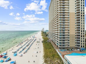 A beachfront hotel with a pool, beach chairs, and umbrellas. - BEACH FRONT MASTER/LR. FREE BCH CHAIRS., INDOOR HEATED POOL, SPA,NEAR PIER PARK (Panama City Beach)