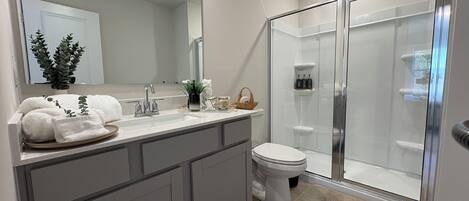 A modern bathroom with a shower, toilet, and vanity.