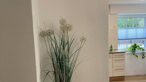 A modern kitchen with wooden cabinets, a window with blinds, and a potted plant on the counter. - Vacation apartment Dorfliebe Minden by Engelmann (Minden)