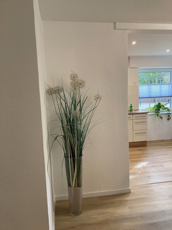 A modern kitchen with wooden cabinets, a window with blinds, and a potted plant on the counter. - Dorfliebe Minden Vacation Apartment by Engelmann (Minden)