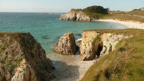Eine Küstenlandschaft mit felsigen Klippen, einem Sandstrand und freiem Blick auf das Meer.