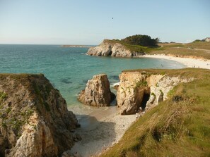 Un paisaje costero con acantilados rocosos, una playa de arena y una vista despejada del mar.